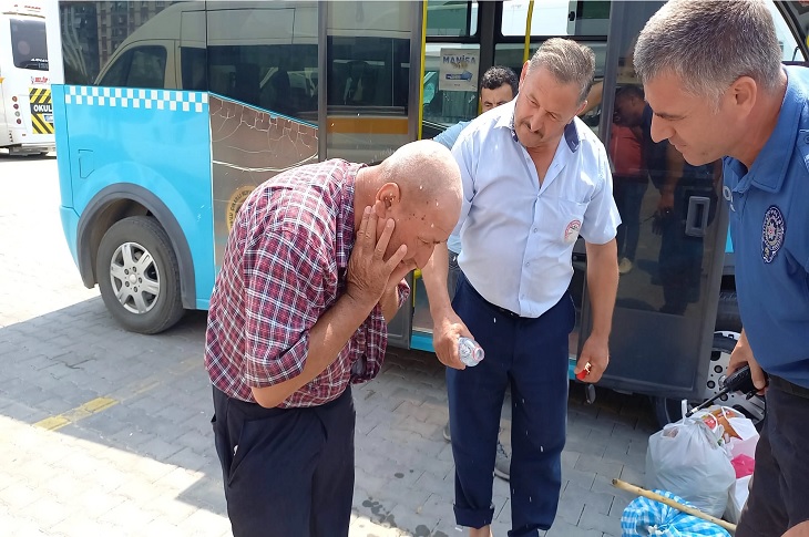 Minibüsten çıkarılan görme engelli yaşlı adamla iletişim halinde olan bir polis memuru objektife yansıyor.