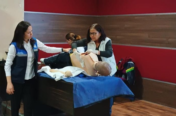 Oyuncak manken üzerinde uygulamalı eğitim gören bir bayan objektife yansıyor.