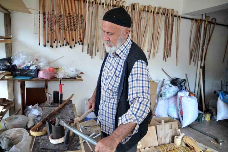 Atölyede baston üretimine devam eden yaşlı adam objektife yansıyor.