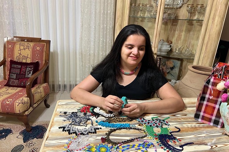 Büşra, masada yapımını tamamladığı takılarla birlikte objektife yansıyor.