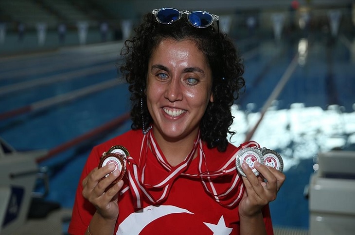 Başarılı sporcu, üzerindeki ay yıldızlı forması ve boyundaki madalyalarıyla objektife yansıyor.