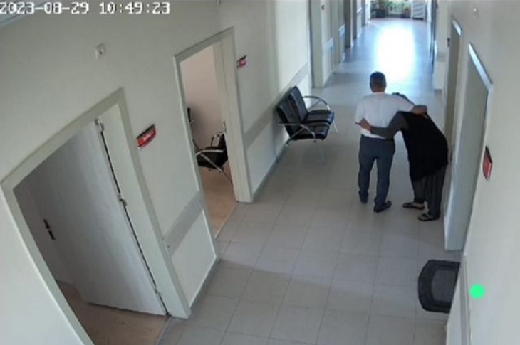 Vakıf müdürünün yaşlı teyzeye sarılarak koridorda beraber ilerlediği ana dair bir kamera görüntüsü objektife yansıyor.