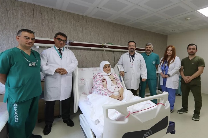 Sağlığına kavuşan kadın hasta, hasta odasını ziyaret eden doktorları ve sağlık görevlileri ile birlikte objektife yansıyor.