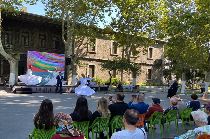 Bahçede kurulan sahnedeki semazenleri seyreden çok sayıda yaşlı birey objektife yansıyor.