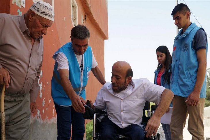 Akülü aracını teslim alan bir engelli birey objektife yansıyor.