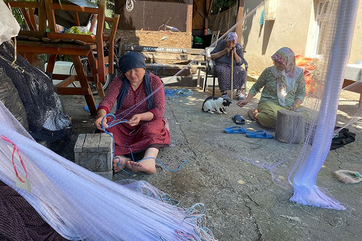 Evin bahçesinde balık ağı ören iki elti objektife yansıyor.