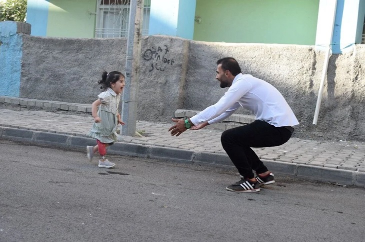 3 yaşındaki Ayda, ayağındaki protez bacak sayesinde, sokakta babasına sarılmak için koşuyor.