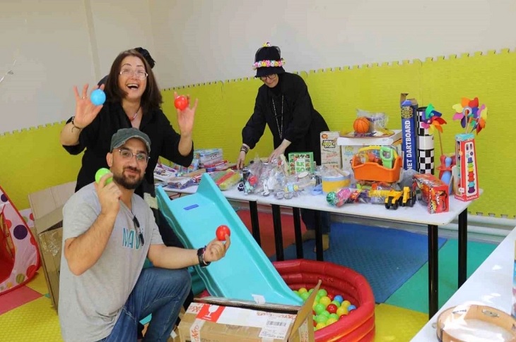 Oyun odasını düzenleyen 3 gönüllü birey objektife yansıyor.