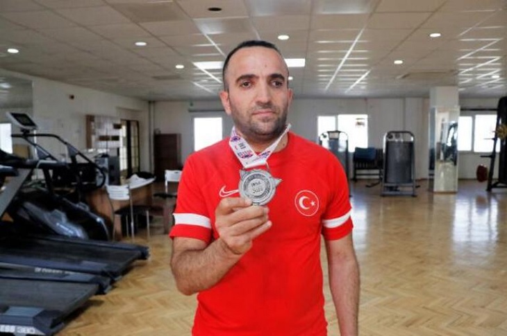 Başarılı sporcu, milli forması ve boynundaki madalyasıyla birlikte objektife yansıyor.