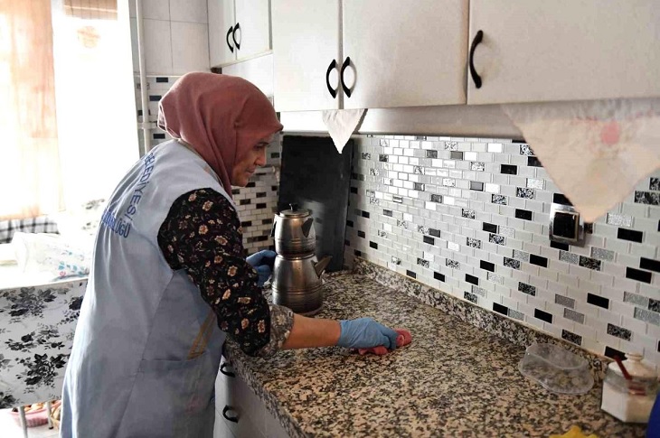 Mutfakta çalışan bir görevli bayan objektife yansıyor.