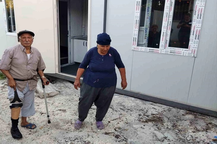 Yaşlı çift, teslim edilen konteyner ev önünde objektife yansıyor.