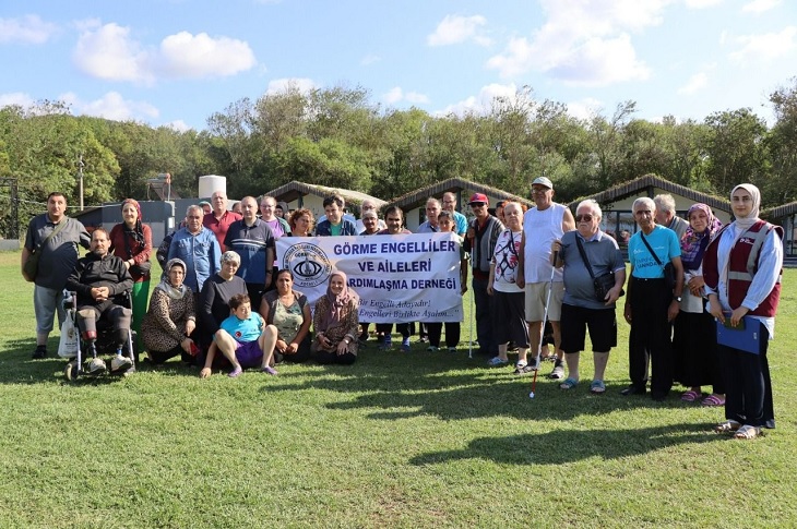 Etkinlikte buluşan görme engelli bireylerin toplu hatıra resmi objektife yansıyor.