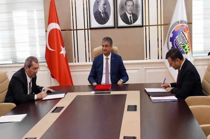 Aynı masada bir araya gelen tarafların imza attığı ana dair bir görüntü objektife yansıyor.