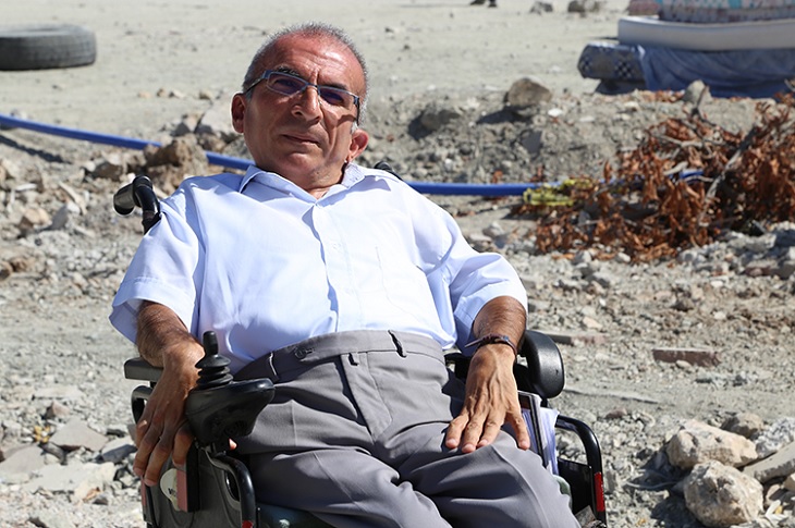 Ali Haydar Koyun, akülü aracıyla enkaz bölgesinde objektife yansıyor.