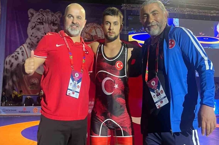 Başarılı sporcu, 2 antrenörü ile birlikte objektife yansıyor.