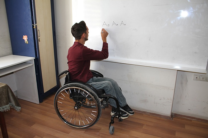 Selçuk'un tahtaya harfleri yazdığı bir resim objektife yansıyor.