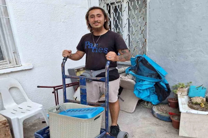 Volkan Başyiğit, elle sürülen geri dönüşüm arabasıyla poz veriyor.