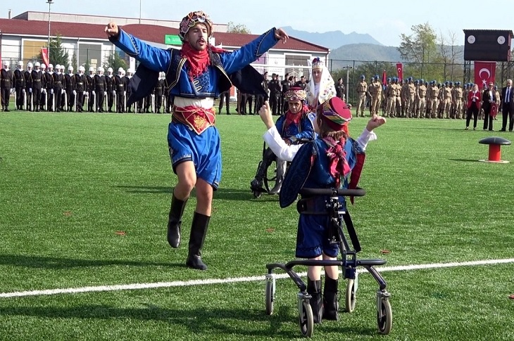 Yeşil alanda düzenlenen etkinlikte, karşılıklı zeybek oynayan bir engelli çocuk objektife yansıyor.