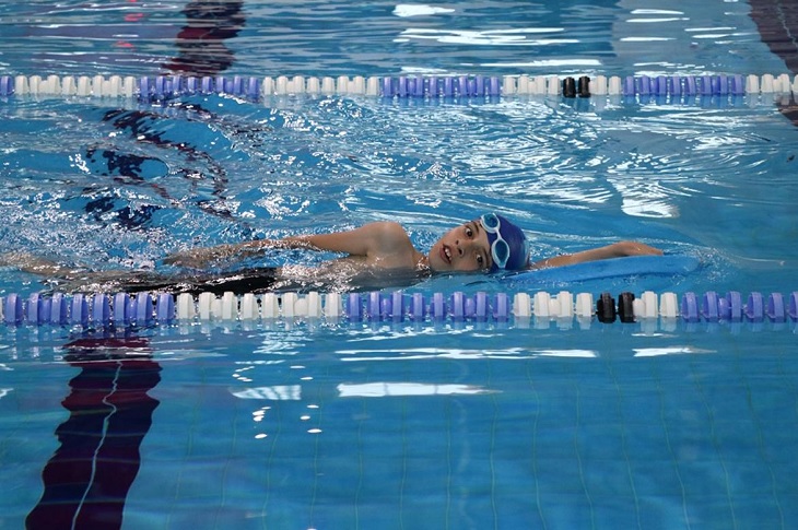 Havuzda kulaç atan başarılı sporcu objektife yansıyor.