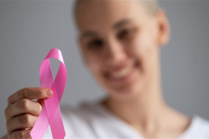 Haberi temsilen, elinde pembe kurdele olan bir kanser hastası bayan objektife yansıyor.