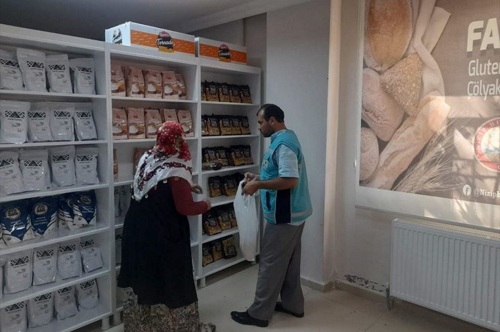 İhtiyaç sahibi bir kadının mağazada talep ettiği gıdaları birebir ilgilenerek veren belediye görevlisi objektife yansıyor.