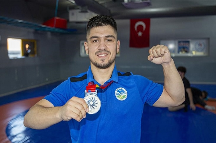 Başarılı sporcu, boynundaki madalyasıyla birlikte objektife yansıyor.