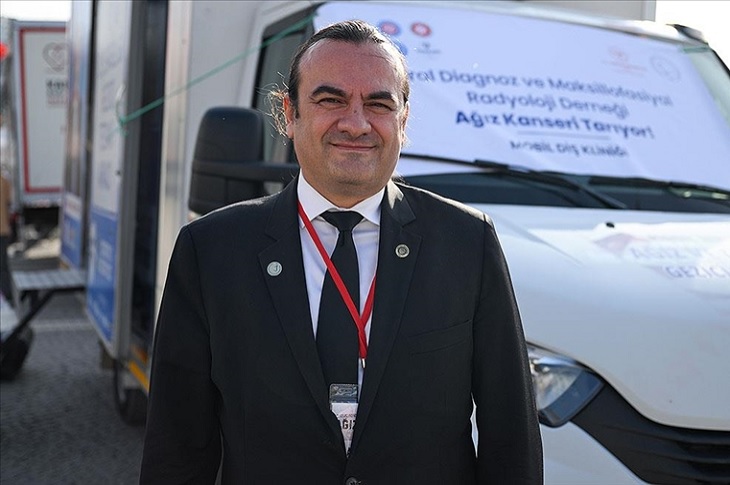 Prof. Dr. Kaan Orhan, ağız ve diş sağlığı mobil aracı önünde objektife yansıyor.