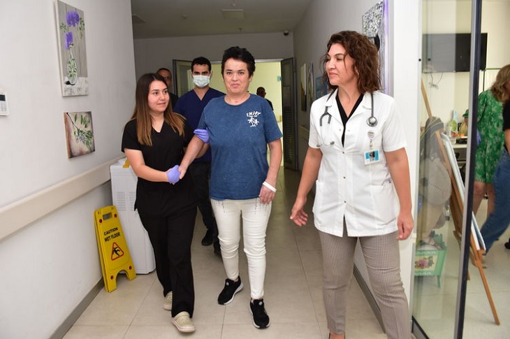 Sağlık görevlilerinin desteğiyle koridorda yürüyen Gülay Polat objektife yansıyor.