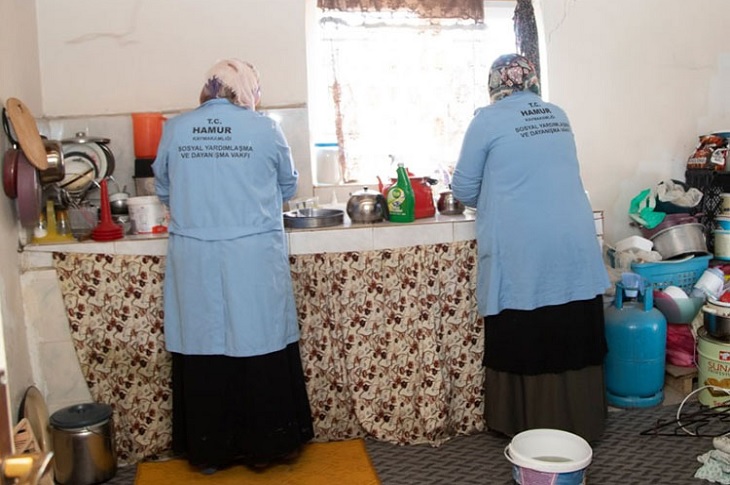 İhtiyaç sahibinin mutfağında çalışan 2 Vefa görevlisi bayan objektife yansıyor.