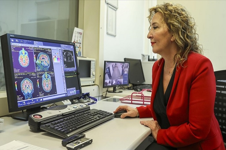 Ekrandaki beyin görüntüsünü inceleyen bir doktor resmi objektife yansıyor.