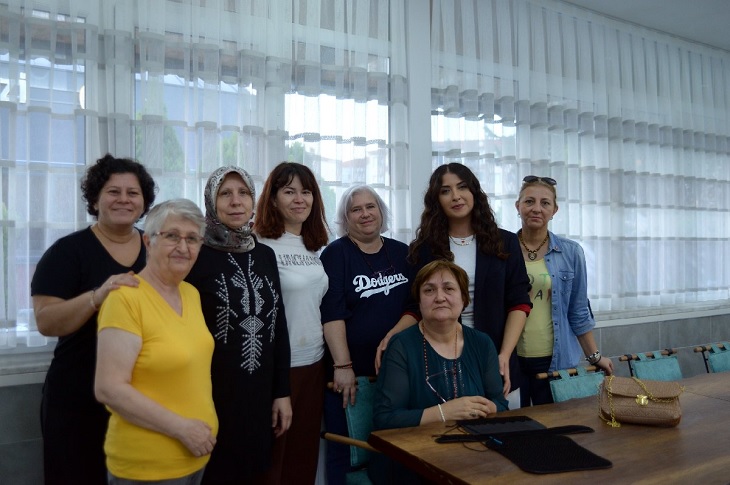 Cemile Teyze'nin atölyedeki iş arkadaşlarıyla birlikte çekilmiş bir toplu hatıra resmi objektife yansıyor.