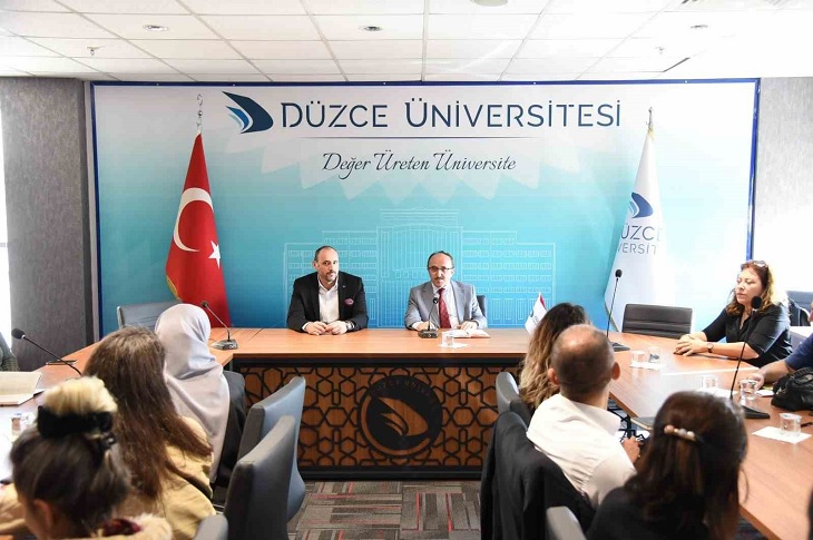 Toplantı masasında bir araya gelen çok sayıda katılımcı objektife yansıyor.