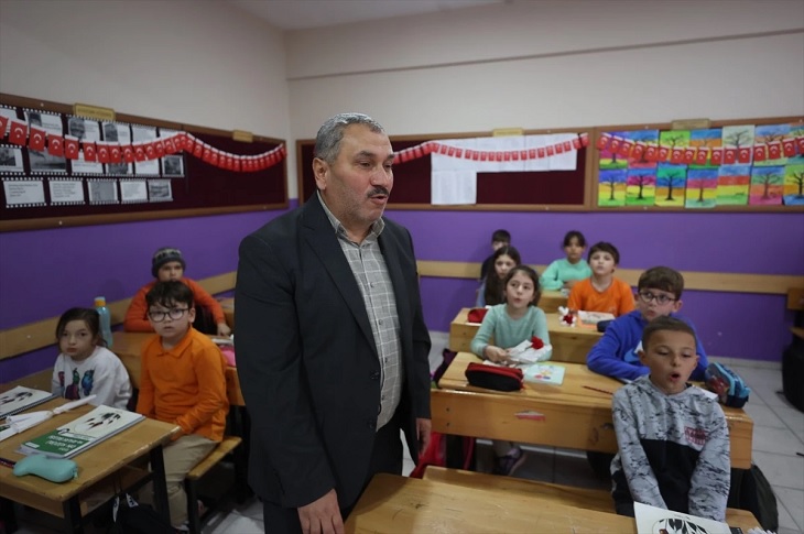 Sabri öğretmenin, sınıftaki öğrencilere ders anlatımında bulunduğu ana dair bir resim objektife yansıyor.