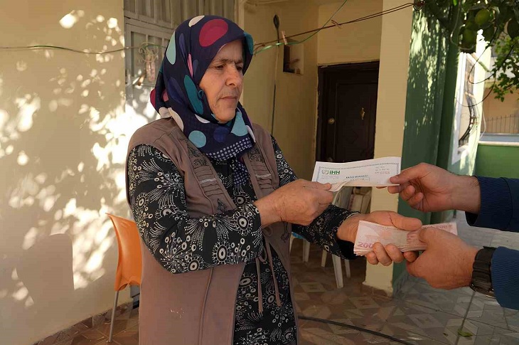 Ev sahibi kadının İHH görevlisine parasını teslim ederek bağış makbuzunu teslim aldığı ana dair bir resim objektife yansıyor.