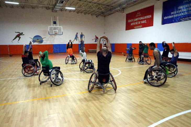 Basketbol sahasında, antrenmanlarına devam eden takım oyuncuları objektife yansıyor.