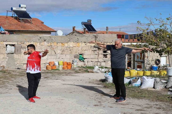 Tarkan öğretmenin, öğrencisiyle birlikte kürek sapıyla antrenman yaptığı ana dair bir resim objektife yansıyor.