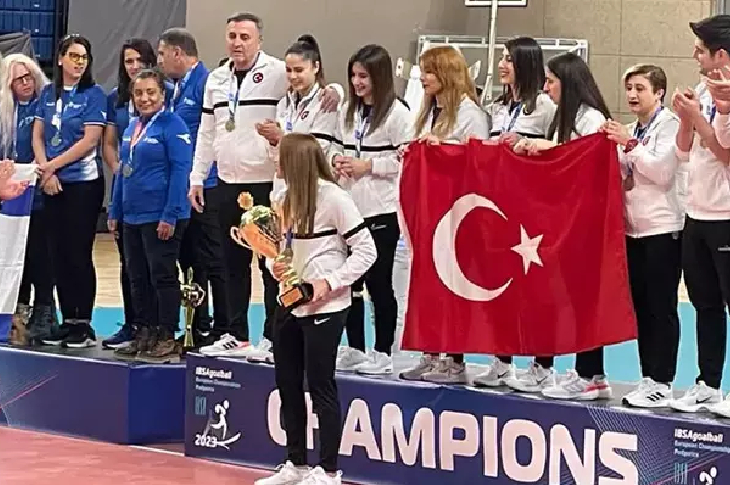 Goalball Kadın Milli Takımı oyuncuları podyumda ellerinde Türk Bayrağı ile kutlama yaparken.