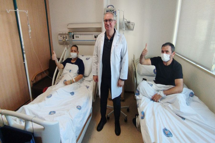 Organ Nakli Merkez Müdürü Prof. Dr. Bülent Aydınlı, yataklarında uzanan çiftin arasında poz veriyor.