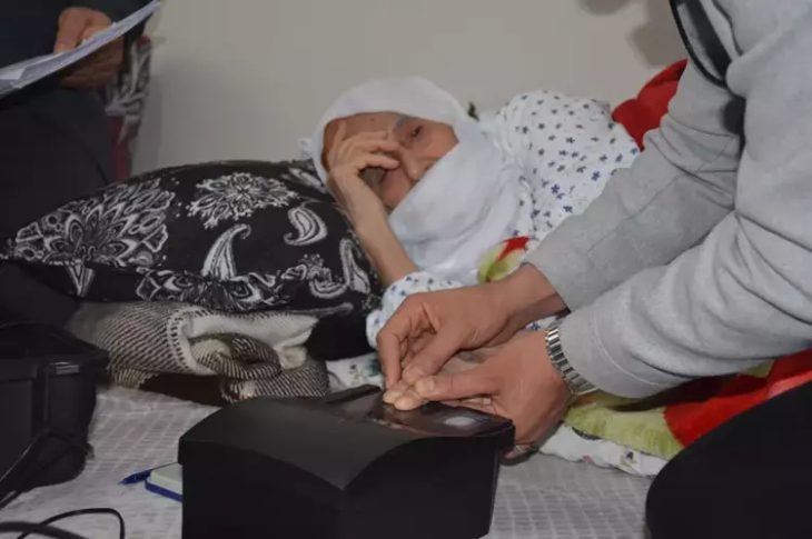 Yatağında uzanan yaşlı kadının parmak izi alınıyor.