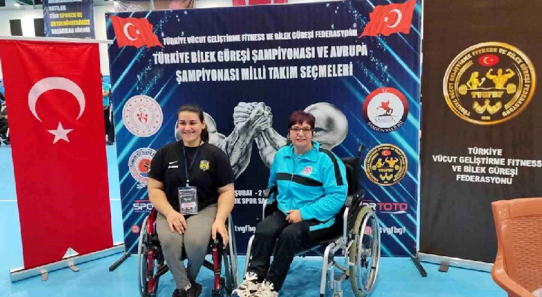 Şampiyon güreşçi stand önünde gülümserken başka bir sporcu ile poz veren görseli