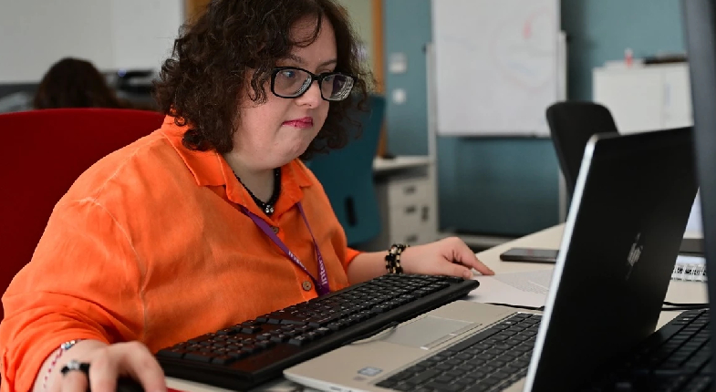 Down sendromlu çalışan masada bilgisayarda çalışırken görseli