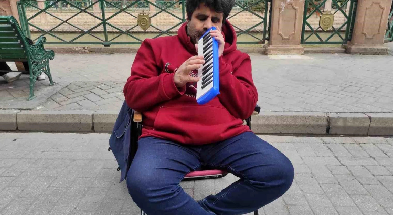 Görme engelli müzisyen sandalyede sokakta sanatını icra ederken