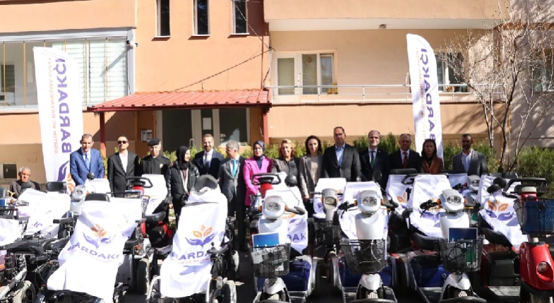 Akülü araçlar ve dernek flamaları ile yetkililer poz verirken