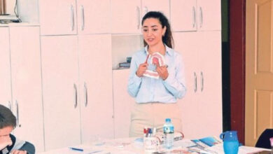 Diş doktoru elinde yapay bir diş tutarak, ağız ve diş sağlığı üzerine eğitim veriyor.