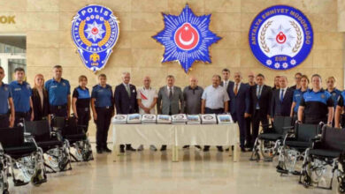 Avrupa El Ele Engellilere ve Yaşlılara Yardım Konfederasyonu yöneticileri ve Antalya İl Emniyet'ne bağlı polisler hayırseverlerin gönderdiği tekerlekli sandalye ile kıyafetlerle fotoğraf çekiliyor.