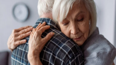 Yaşlı bir adam ve kadın birbirine sarılmış.