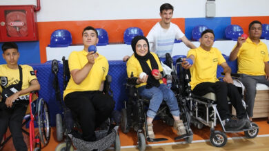 Serebral palsili öğretmen Yavuz Öndem, tekerlekli sandalye kullanıcısı sporcular ile birlikte fotoğraf karesinde yer alıyor.