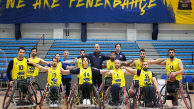 Fenerbahçe Göksel Çelik Tekerlekli Sandalye Basketbol Takımı sporcuları tekerlekli sandalyeleri ile önden arkaya doğru iki sıra şeklinde, yan yana durmakta ve ellerini birbirlerinin omuzlarına katmışlar.