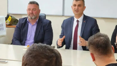 Gölcük Belediye Başkanı Ali Yıldırım Sezer, beyaz bir masanın etrafında yer alan engelli bireylerle konuşuyor.