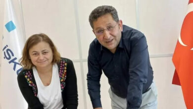 Bir kadın ve erkek masaya doğru eğilmektedir.